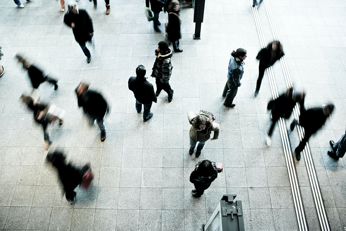 A crowd of people walking in different directions, photographed from above. Photo by Timon Studler, via Unsplash