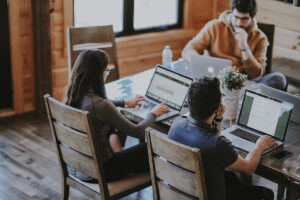 Three young people working with laptops around a table. Photo by Annie Spratt, via Unsplash