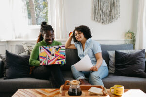 Two people sitting on a sofa, looking at a laptop. Photo by Surface, via Unsplash