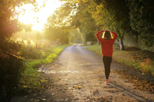 Female runner standing on a path with hands on head contemplating the road ahead