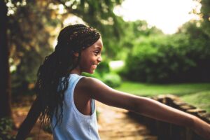 Young girl with braids, smiling outside in forest