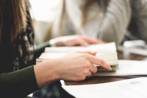 Hands holding open text book on desk