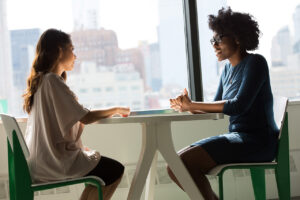 Two women sitting at a table and talking - photo by Christina at wocintechchat.com - via Unsplash