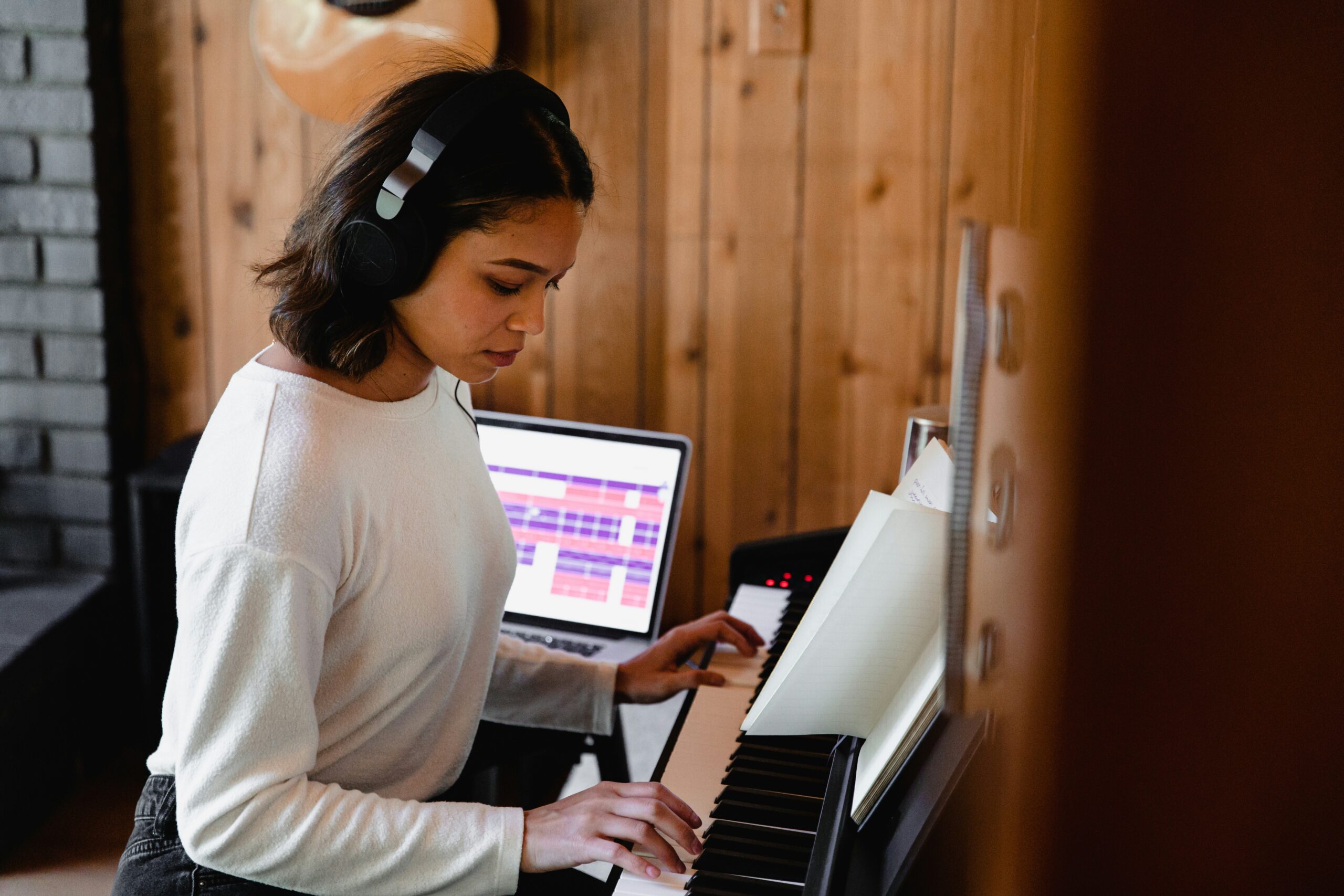 Woman wearing headphones at keyboard writing song