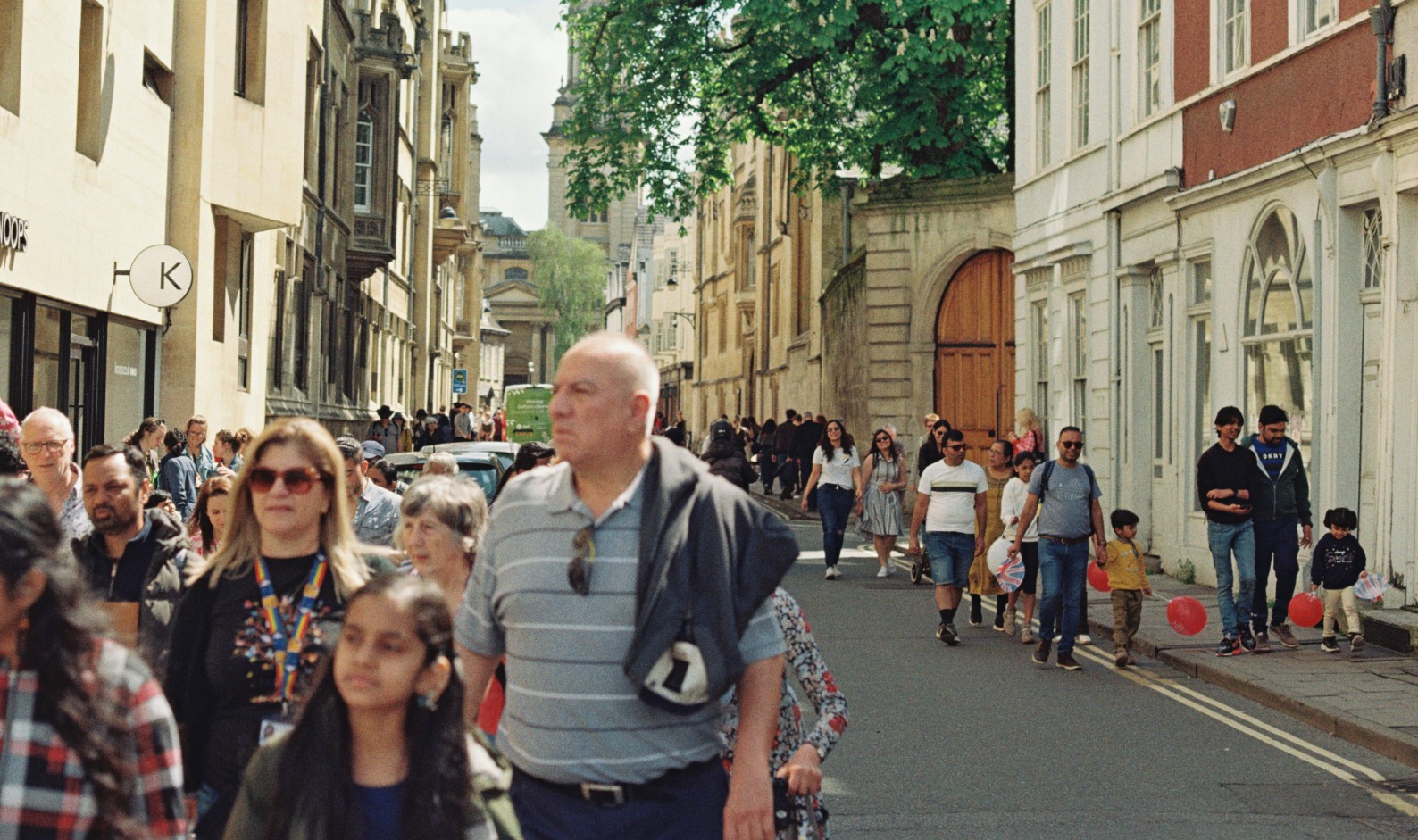 Crowd walking through Oxford city street on summer's day